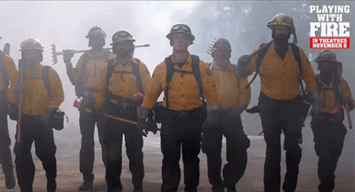 Firefighters Standing In Front Of Playing With Fire Sign GIF