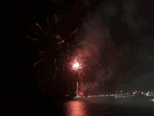 Fireworks Are Displayed Over A Body Of Water In The Night Sky GIF