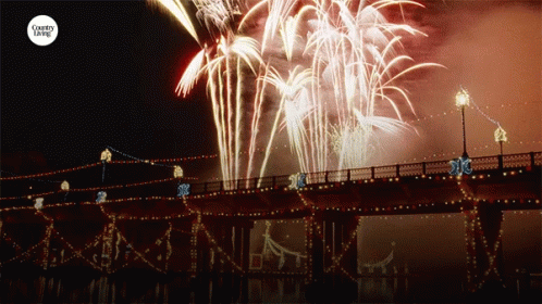 Fireworks Are Displayed Over A Bridge With The Words Country Living On The Bottom GIF