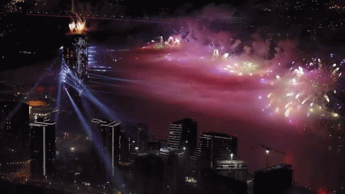 fireworks are displayed over a city with a purple sky in the background