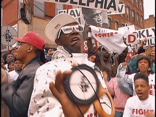 Flavor Flav Showing Off His Necklace GIF