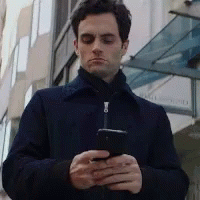 Focused Joe Goldberg Holding Cellphone GIF
