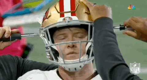 Football Player Being Adjusted by Person