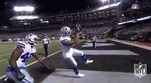 Football Player Catching Pass While Another Watches