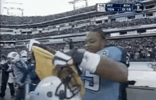 Football Player Holding Helmet And Flag In Front Of Crowd GIF