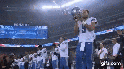 Football Player Holding Trophy in Front of Verizon Sign