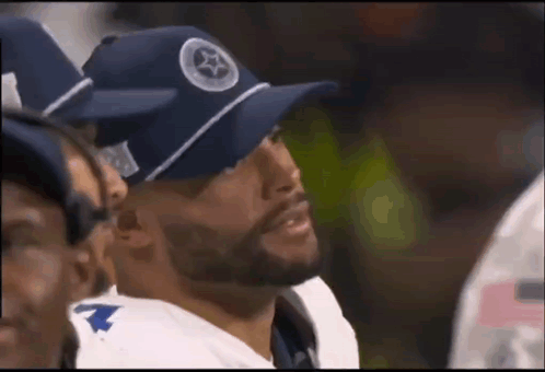 Football Player in Blue Hat Sitting in Huddle