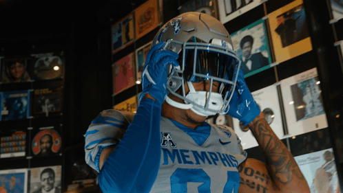 Football Player in Memphis Jersey and Helmet in Front of CD Wall