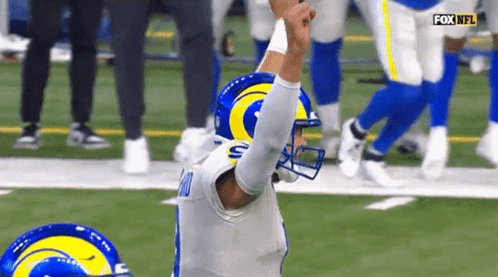 Football Player in Rams Helmet Kneeling on Field