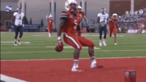 Football Player in Red Jersey Being Tackled by White Jersey