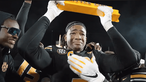 Football Player in SEC Jersey Holding Yellow Trophy