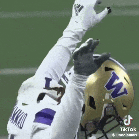 Football Player in White Jersey and Purple Helmet Reaching Up