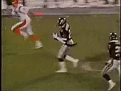 Football Player Jumping to Catch Ball With Defender
