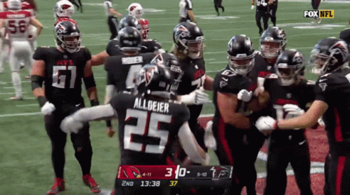 Football Player Number 25 Surrounded By Teammates GIF