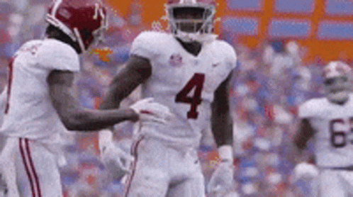 Football Player Number 4 Being Helped by Teammate