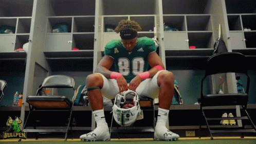 Football Player Sits in Locker Room Number 80
