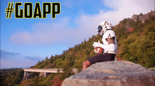 Football Player Sitting on Rock Holding Football #GoApp