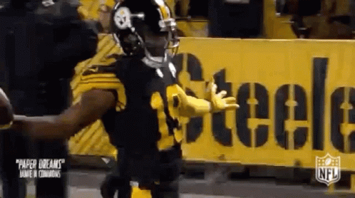Football Player Standing In Front Of Yellow Sign GIF