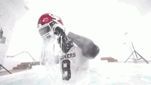 Football Player Standing in Pool With Water Pouring on Head