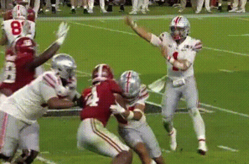 Football Player Throwing Pass While Being Tackled