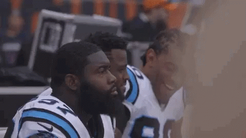 Football Players Huddle on Sidelines