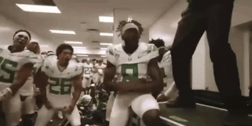 Football Players in Green and White Dancing in Hallway