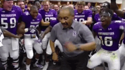 Football Players in Purple Uniforms Dancing With Man in Grey Shirt