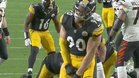 Football Players on Field One Holding Pants Up