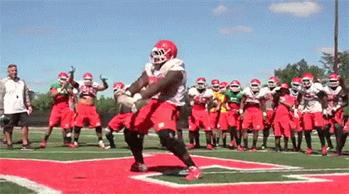 Football Players on Field One in Red Helmet