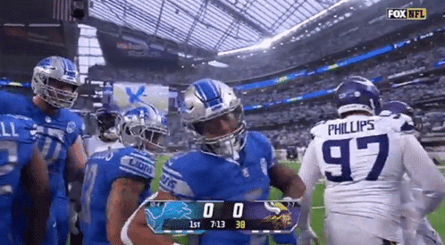 Football Players Standing on Field With Scoreboard