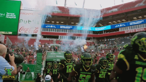 Football Players Walking Into Stadium Sponsored by Jabil and Coca-Cola