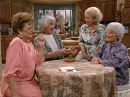 Four Older Women Are Sitting Around A Table In A Kitchen . GIF