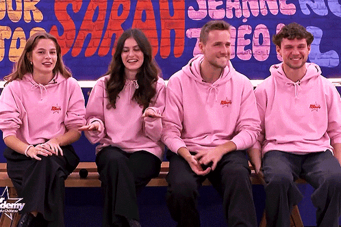 Four People In Pink Hoodies Sitting At Sign GIF
