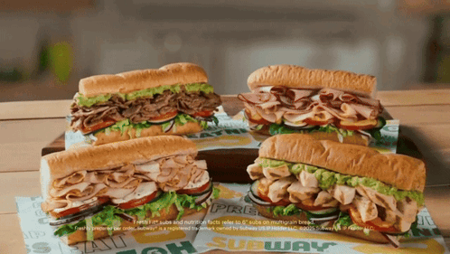 Four Subway Sandwiches Are Sitting On A Table GIF