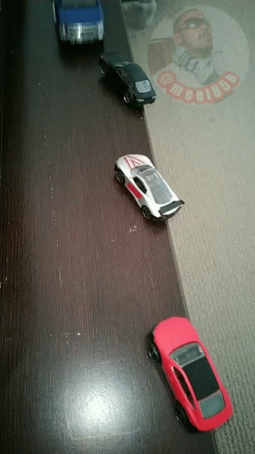 Four Toy Cars Lined Up With Man in Sunglasses And Text Megi85p