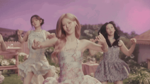 Four Women Are Dancing In Front Of A House In A Garden GIF