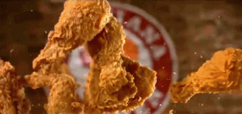 Fried Chicken Is Falling On A Plate With A Kfc Sign In The Background GIF