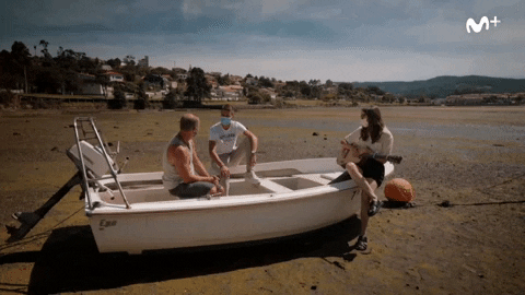 Friends Sitting On Skiff Talking Near Shore GIF