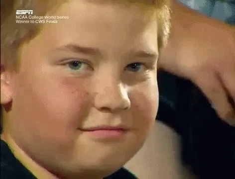 gif of a kid at some sort of sporting event. he has the buzz mccallister buzz cut and freckles. he is looking directly at the camera with a knowing smile as he wags his eyebrows and shimmies his shoulders