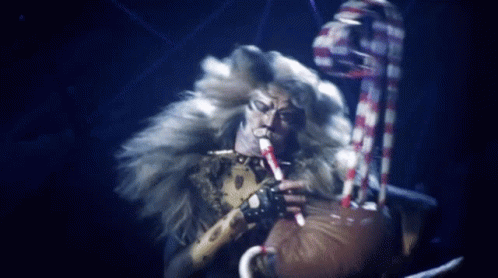 Furry Man Playing Flute in Dark Room