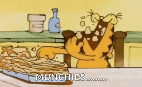 Garfield Is Sitting At A Table Eating A Piece Of Lasagna . GIF