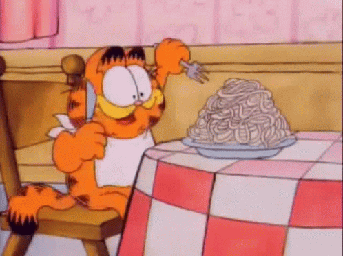 Garfield Is Sitting At A Table With A Plate Of Spaghetti On It . GIF