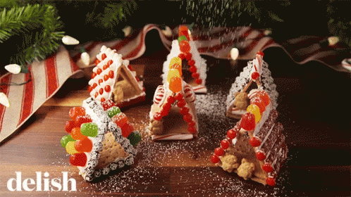 Gingerbread Houses Made Out Of Graham Crackers And Candy Are On A Table With The Word Delish In The Corner GIF