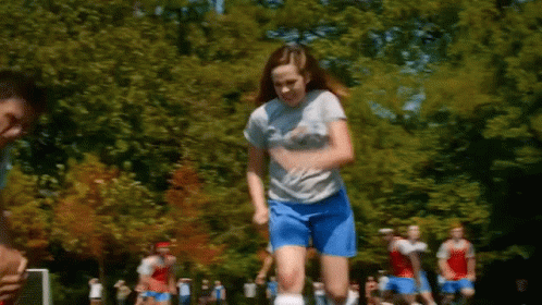Girl in Blue Shorts Jumping While Playing Soccer