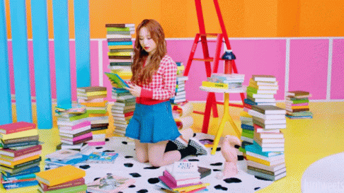 Girl in Blue Skirt Reading Surrounded by Book Stacks