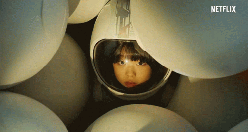 Girl In Helmet Surrounded By White Balls GIF