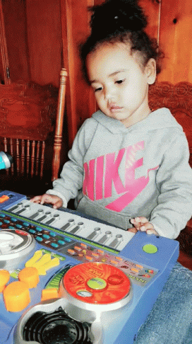 Girl in Nike Shirt Playing Toy Keyboard