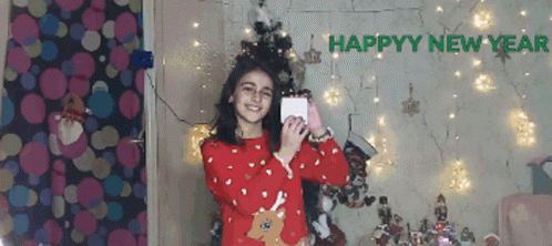 Girl in Red Sweater Taking Selfie in Front of Happy New Year Sign