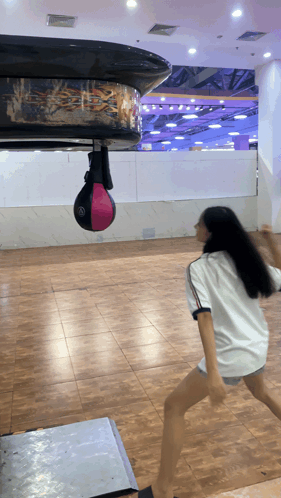 Girl in White Shirt Playing With Punching Bag