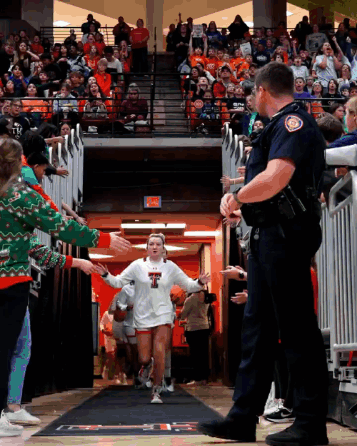 Girl in White Shirt With Letter T Walking Through Crowd